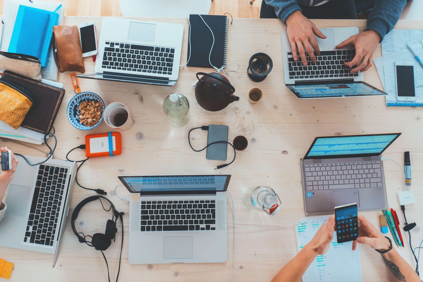 Bird's eye view of a group of people sitting at a table using laptop computers.