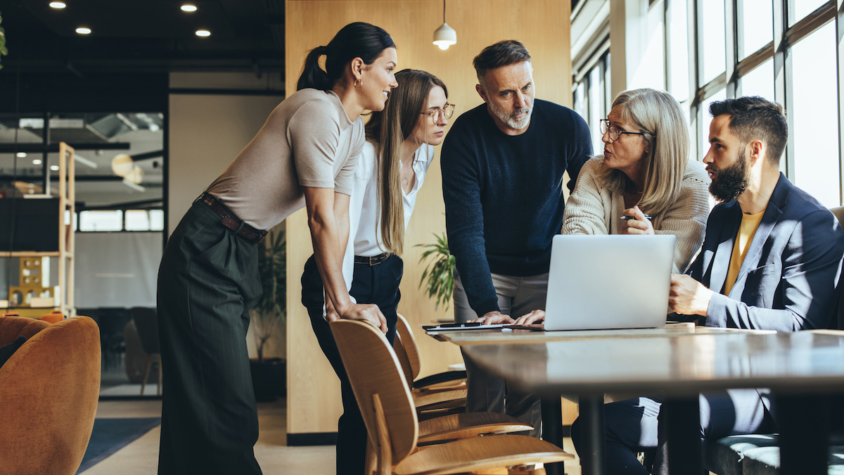 People in an office standing around a table discussing talent acquisition