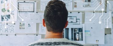 Man looking at wall of recruitment plans on paper considering how to use AI