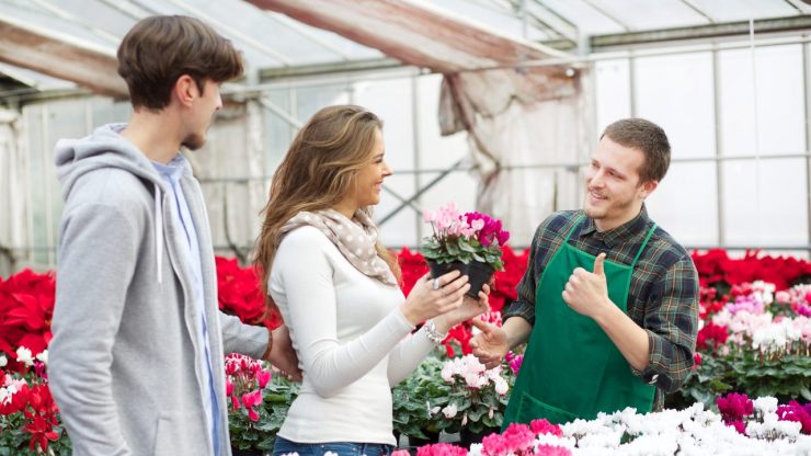 retail associate selling flowers to a couple at a gardening store